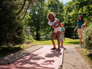 Participants profitant d’une partie de mini-golf en plein air à Atout Branches, activité ludique pour enfants et adultes dans un cadre naturel.